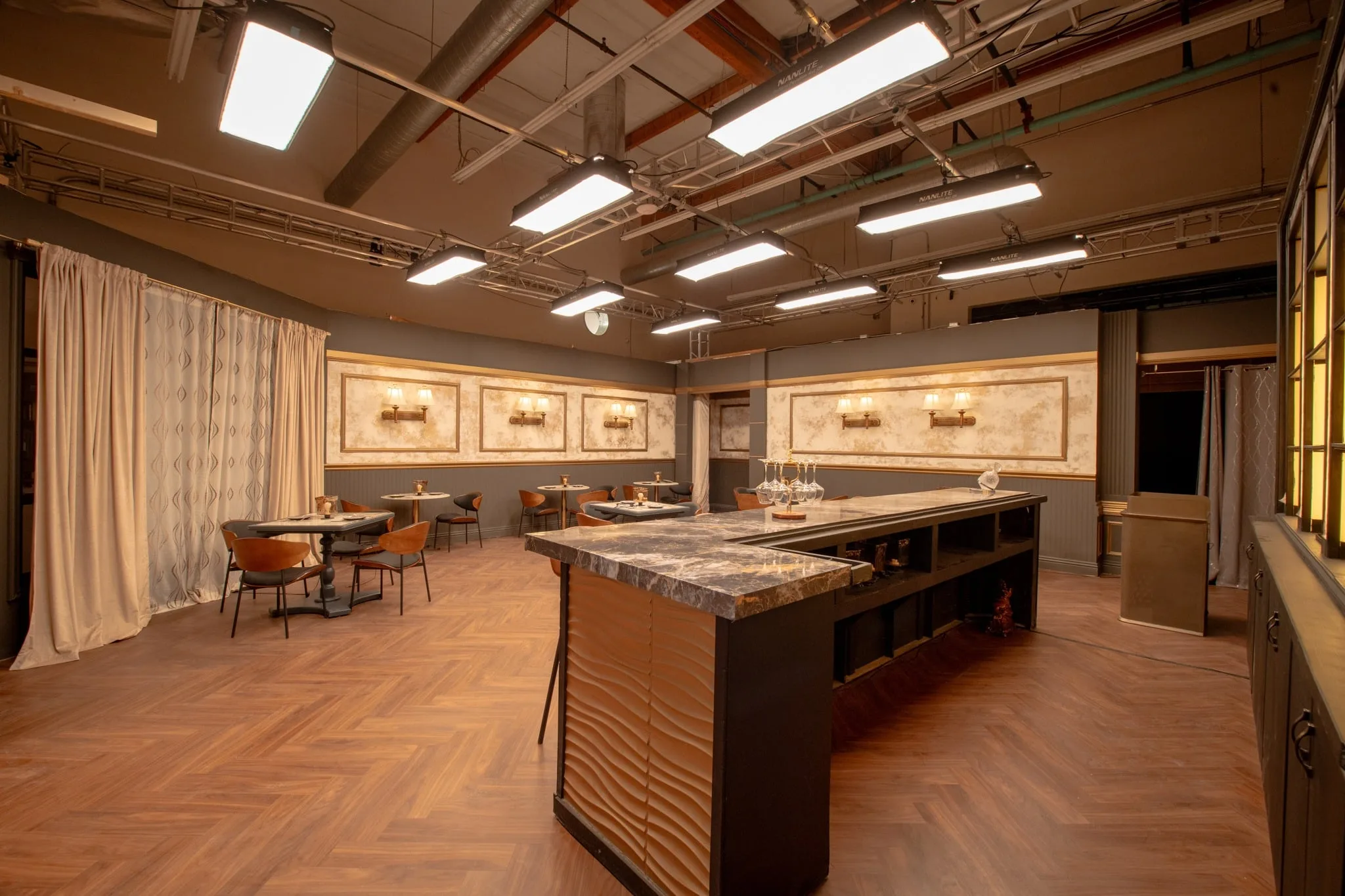 A fully dressed restaurant set beneath a grid of studio lighting fixtures.